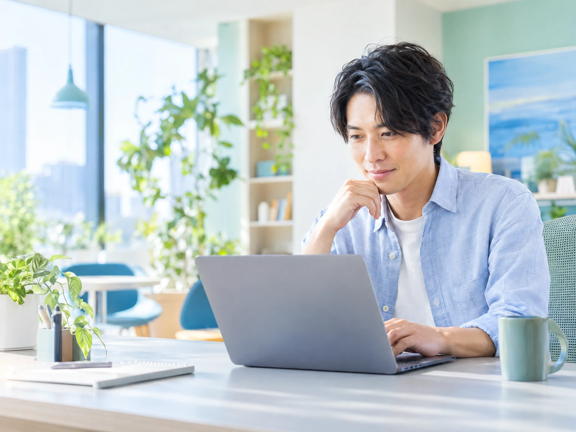 明るいオフィスでノートパソコンの設定を確認するエンジニア